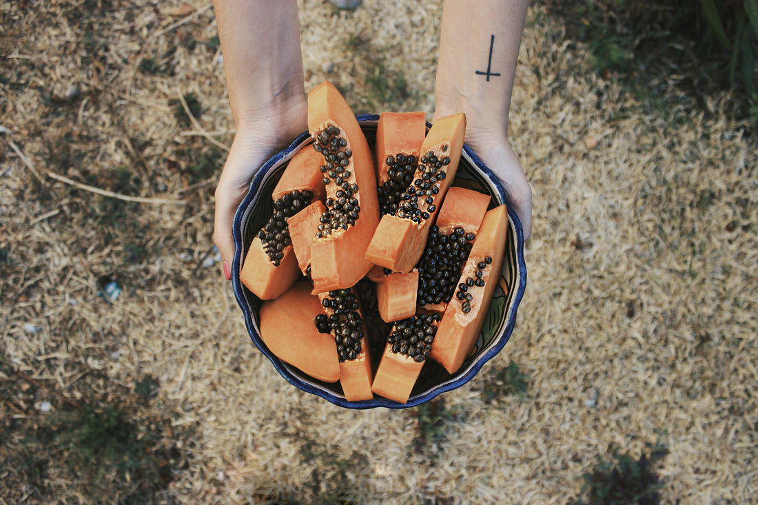 hands holding bowl of sliced papaya fruit